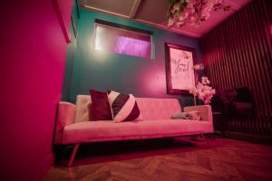 - un canapé rose dans le salon avec éclairage rose dans l'établissement The Ultimate Hen Suite with Bar & Makeup Room, à Manchester