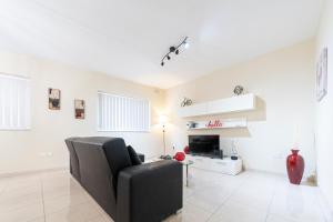 un salon avec une chaise noire et une télévision dans l'établissement Modern 2 Bedroom Apartment 2 minutes to Seafront, à San Pawl il-Baħar