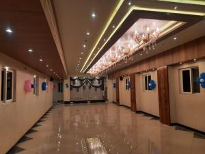 un corridoio con lampadario a braccio e un lungo corridoio con porte di Hotel Sannidhi a Vijayawāda
