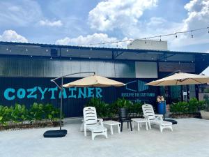 a group of chairs and umbrellas in front of a building at Reserve The Cozytainer in Taiping