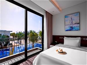 ディエン・バンにあるHoang Yen Boutique Hotelのベッドと大きな窓が備わるホテルルームです。