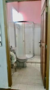 uma casa de banho com um chuveiro e um WC. em Sewa Rumah 4 Kamar Tidur em Bandung