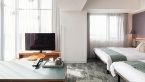 a hotel room with two beds and a flat screen tv at REF Okinawa Arena by VESSEL HOTELS in Okinawa City