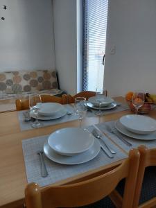 a wooden table with plates and wine glasses on it at Apartmani Romana in Punat