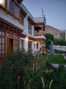 a building with a yard with flowers and an umbrella at Namra Villa in Leh