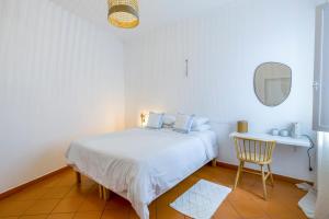 a white bedroom with a bed and a chair at Casa Luma B&B in Lagos