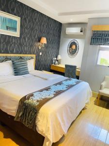 a bedroom with a large bed and a desk at Aquarian Tide Hotel in Gaborone