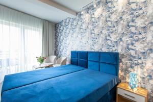 Una cama azul en un dormitorio con una pared azul en Bursztynowa Przystań, en Grzybowo
