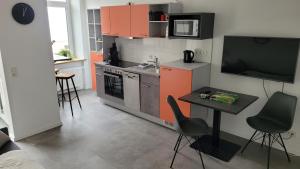 a kitchen with orange cabinets and a table and a television at Fewo Dörrberg in Waldmohr