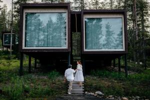 Un uomo e una donna che camminano su per le scale di fronte a un edificio di Arctic TreeHouse Hotel a Rovaniemi