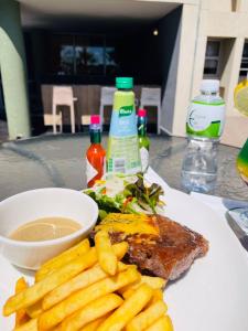 Aquarian Tide Hotel في غابورون: طبق من الطعام مع شريحة لحم وبطاطس مقلية