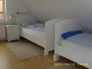 twee witte bedden in een kamer met een nachtkastje bij Fennas Ferienwohnungen - Hanne in Dornumersiel +2 foto's