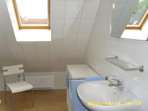 een badkamer met een wastafel, een spiegel en een stoel bij Fennas Ferienwohnungen - Hanne in Dornumersiel