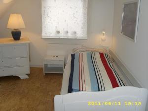 een slaapkamer met een bed, een ladekast en een raam bij Fennas Ferienwohnungen - Hanne in Dornumersiel