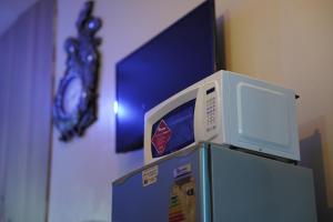 Elle comprend un four micro-ondes et un réfrigérateur avec une horloge. dans l'établissement Serenity Retreat, à Nairobi