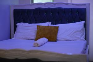- un lit avec une tête de lit bleue, un oreiller et un animal rembourré dans l'établissement Serenity Retreat, à Nairobi