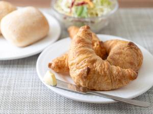 a plate of food with a croissant and a knife at Super Hotel Tozai line Ichikawa Myoden Ekimae in Ichikawa