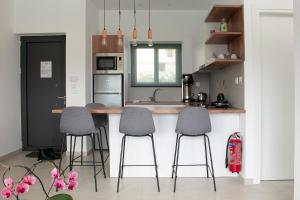 a kitchen with three bar stools and a kitchen counter at Rose Cozy Getaway - 3 Pearls Pool Retreat in Dhémbla