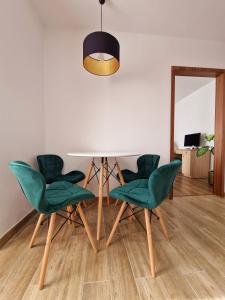 uma sala de jantar com uma mesa e cadeiras verdes em House of flowers em Petroşani