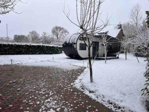 een huis in de sneeuw met een vat bij Tinyhouse Friesland 