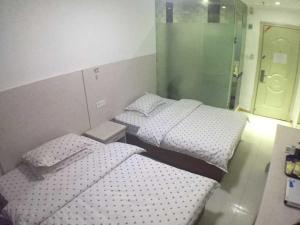 two twin beds in a room with a door at Seven Orange Hotel in Shenzhen