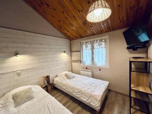 a bedroom with two beds and a tv in it at Au Chalet d'Aline - Atypique pour 4 personnes in Gérardmer