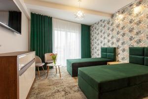 um quarto de hotel com mobiliário verde e um sofá em Bursztynowa Przystań em Grzybowo