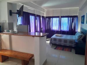 Cette chambre dispose de rideaux violets et d'un lit. dans l'établissement Umkomaas Lodge, à Umkomaas