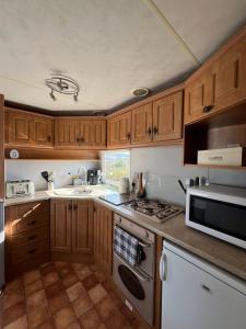 a kitchen with wooden cabinets and a stove top oven at Holiday Home by the sea in Aberystwyth
