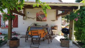 patio con tavolo e sedie sotto un pergolato di La petite parenthèse a Muides-sur-Loire