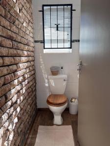 a bathroom with a toilet with a window and a brick wall at Aan d'Oewer in Citrusdal