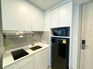 a kitchen with white cabinets and a black refrigerator at Квартира с видом на сад Laguna 1313 от IBGProperty in Phuket