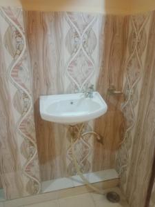 W łazience z drewnianymi ścianami znajduje się biała umywalka. w obiekcie Aanand Bhwan dharmshala ayodhya w mieście Ayodhya