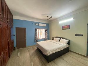 Un dormitorio con una cama con paredes azules y una ventana en Sejour D Confort (Bamboo Stays) en Pondicherry