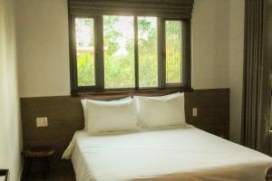 a bedroom with a bed with two pillows and a window at MyGarden Villa Binh Chau Hotspring in Binh Chau