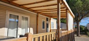 a wooden porch with awning on a house at Kokua Développement présente MOBIL HOME résidentiel toutes options camping 4 étoiles CANET in Canet-en-Roussillon