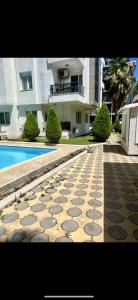 a tile walkway in front of a building with a swimming pool at confort residance in Antalya