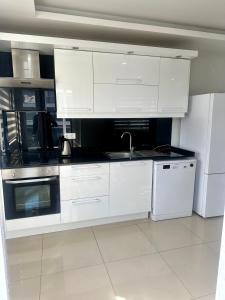 a white kitchen with a sink and a refrigerator at confort residance in Antalya