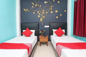 una camera con due letti con cuscini rossi di OYO Flagship Fun Friday Guesthouse a Bodh Gaya
