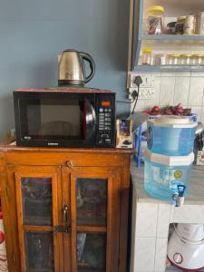 a microwave sitting on top of a cabinet in a kitchen at Maayaa Ridge House in Kanatal