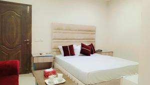 een slaapkamer met een groot wit bed en een rode stoel bij HOTEL MEDALLION EXPO in Lahore