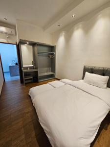- une chambre avec un grand lit blanc et une grande fenêtre dans l'établissement AKSHAYA VILLA SUKABUMI, à Sukabumi