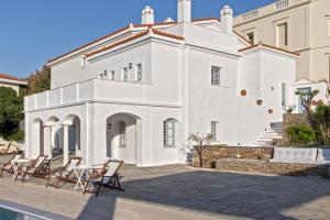 ein weißes Haus mit Stühlen davor in der Unterkunft Androspremiumvillas in Ándros