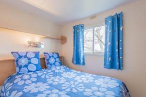 a bedroom with a blue bed with blue curtains at Mobilhome au vert in Roquebrune-sur-Argens