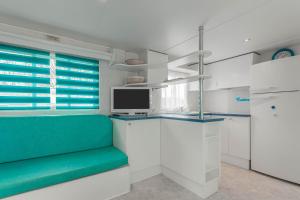 a kitchen with white cabinets and a green couch at Mobilhome au vert in Roquebrune-sur-Argens