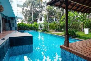 uma grande piscina azul com um deque de madeira em Casa Verde · Luxurious 3BHK Villa in Goa Velha em Goa