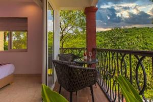 een balkon met een bed en een tafel en stoelen bij Luxurious Apartment with a Pool near Candolim 11 in Goa