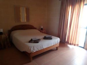 a bedroom with a bed with two shoes on it at Bed and Breakfast Dar Tal-Lumija in Għajnsielem