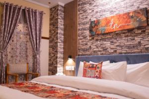 1 dormitorio con cama y pared de ladrillo en The nexus Hotel Apartments, en Peshawar