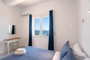 a bedroom with a blue bed and a window at Punda Beach Seaside Retreat in Logaras